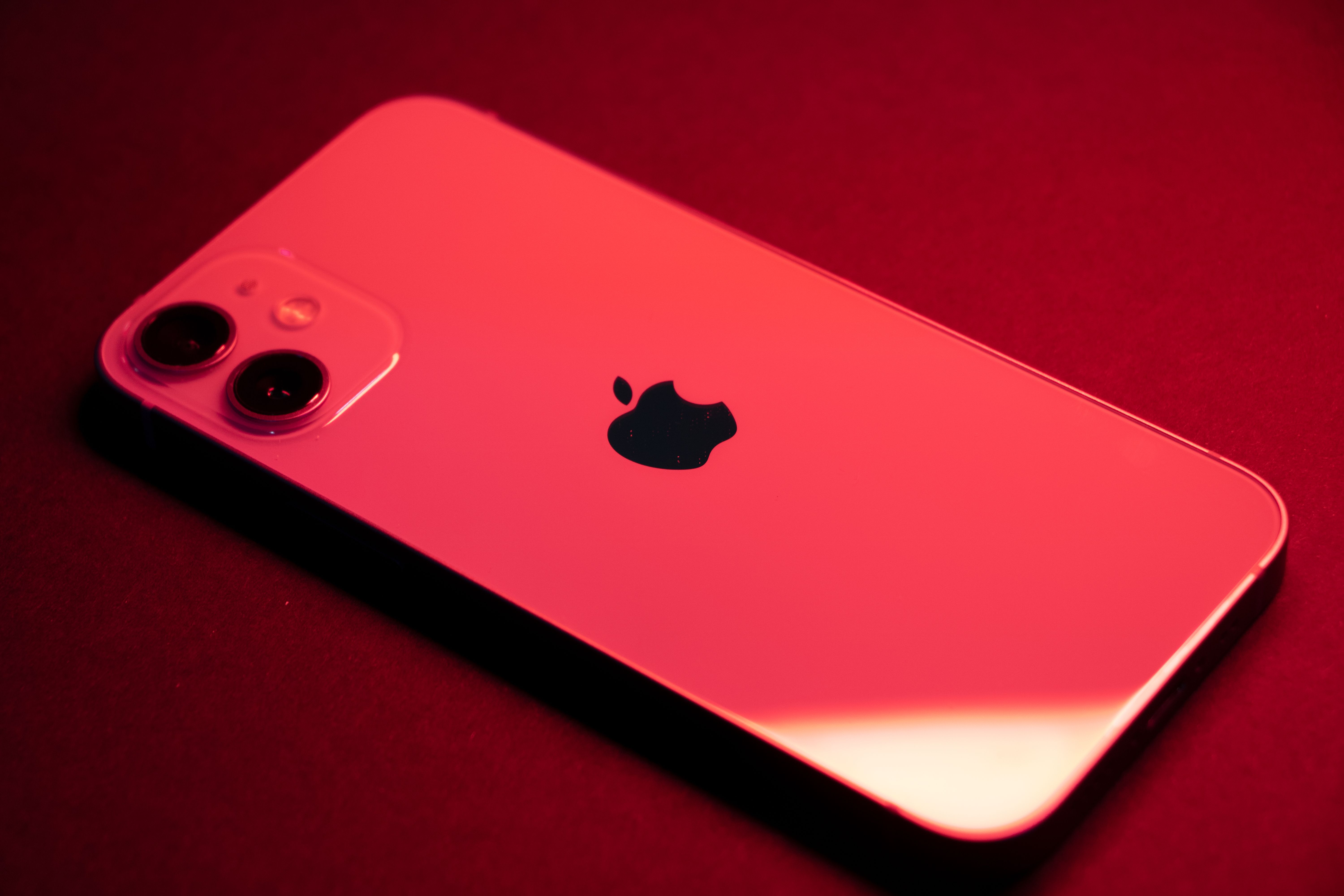 A close-up of a red iPhone on a dark background